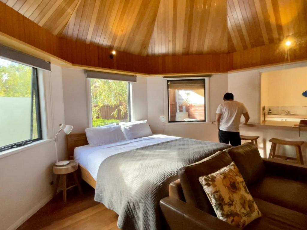 a man is standing in a bedroom with a bed at Grape Juice Retreat in Margaret River Town