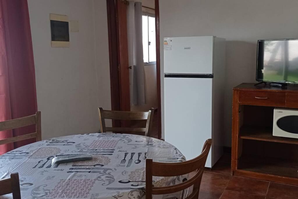 a kitchen with a table and a white refrigerator at Apto. en Colonia, a 1 cuadra de la Plaza de Toros in Colonia del Sacramento