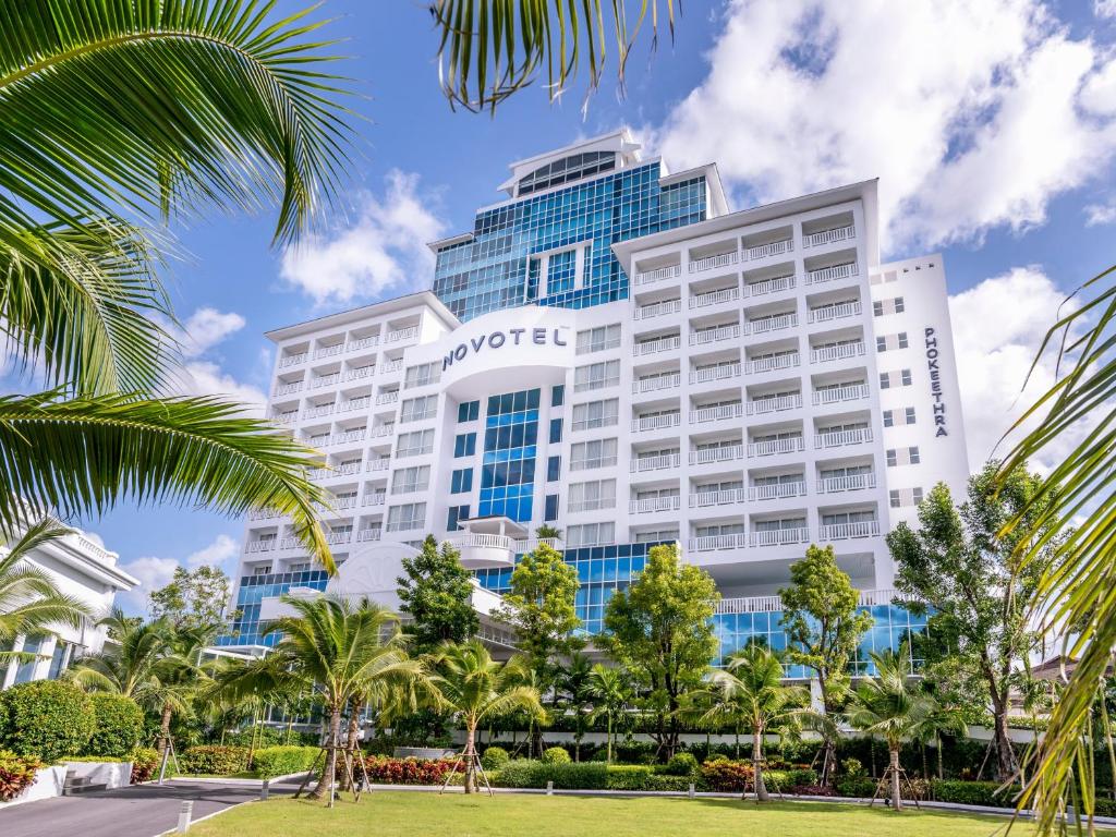 a hotel with palm trees in front of a building at Novotel Phuket City Phokeethra in Phuket Town