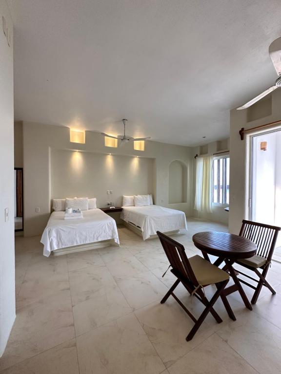 um quarto com 2 camas, uma mesa e cadeiras em Hotel Estrella de Mar em Zipolite