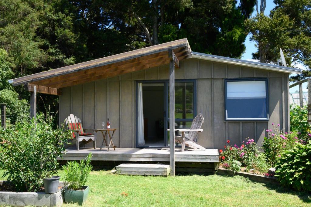 uma pequena cabana com uma mesa e cadeiras num quintal em The Hen House em Kaipara Flats