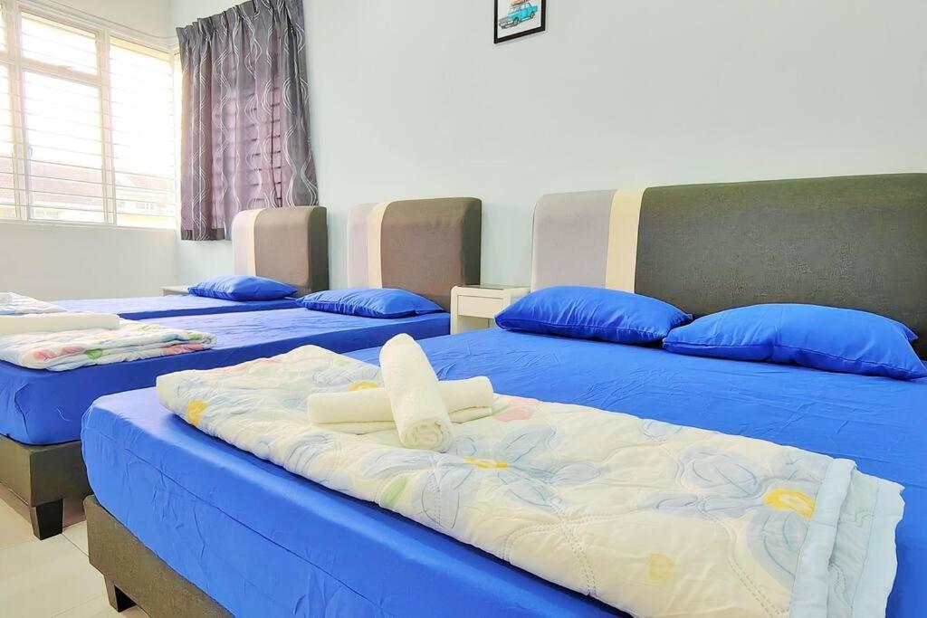 three beds in a room with blue sheets and blue pillows at Equine Park Landed H.stay-Farm in the City-12Pax in Seri Kembangan
