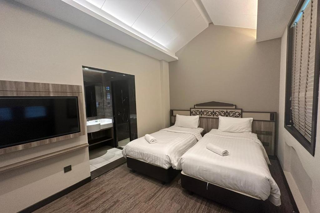 a hotel room with two beds and a flat screen tv at Lion Peak Hotel Hamilton in Singapore