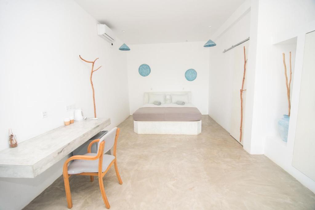a white bedroom with a bed and a chair at NAVA b&b in Mirissa