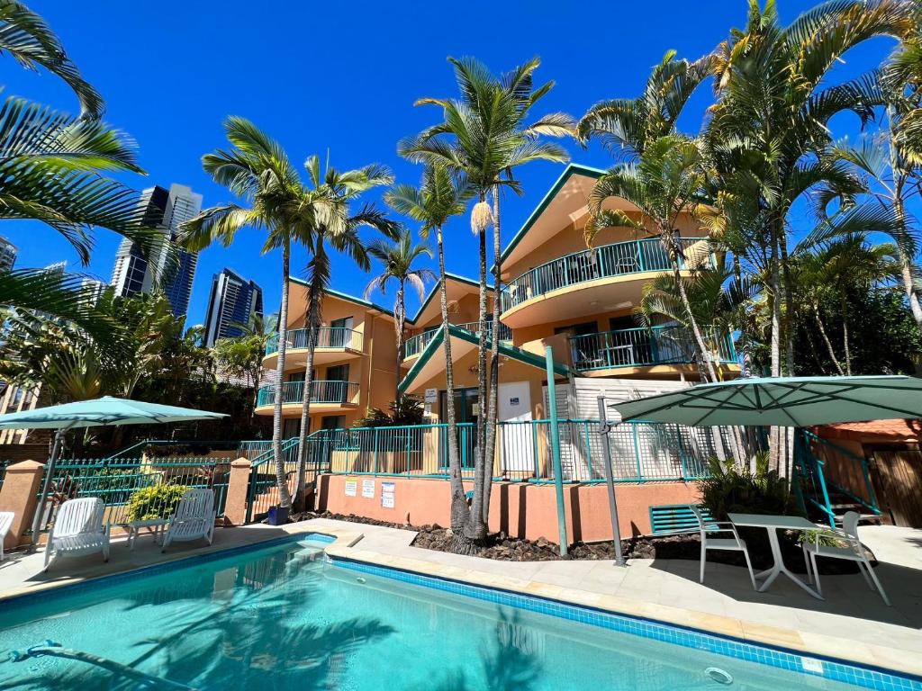 uma piscina de resort com palmeiras e um edifício em Karana Palms Resort em Gold Coast