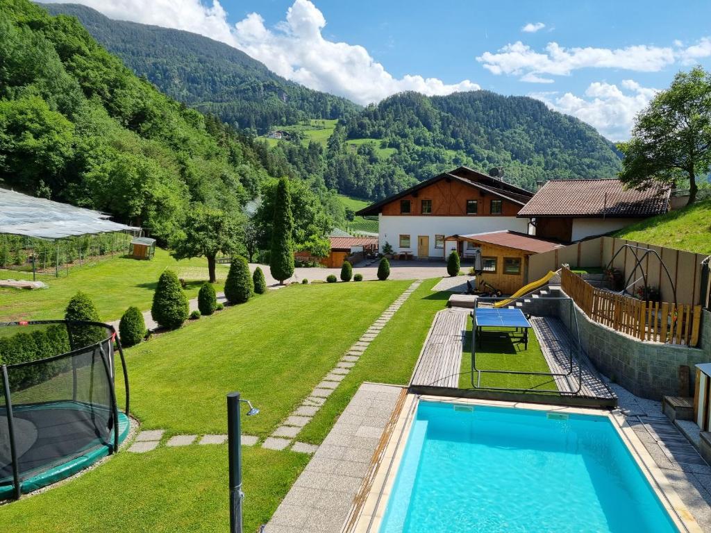 a backyard with a swimming pool and a house at Ferienwohnungen Koflerhof in Castelrotto