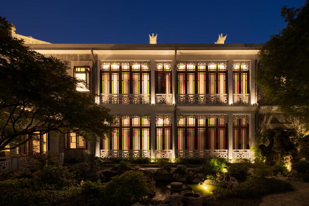 Hangzhou Qiushui Villa في هانغتشو: مبنى أبيض كبير مع نوافذ مضاءة في الليل