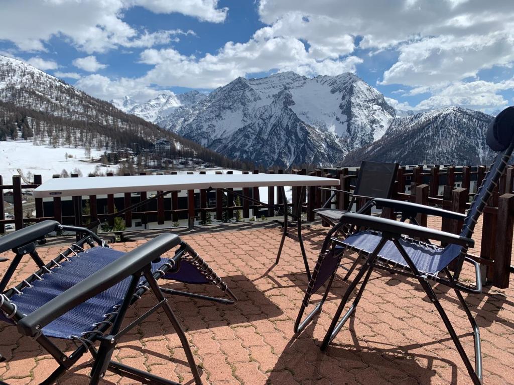 un tavolo e sedie seduti su un patio con montagne di Monolocale con terrazzo e vista spettacolare sui monti a Sestriere