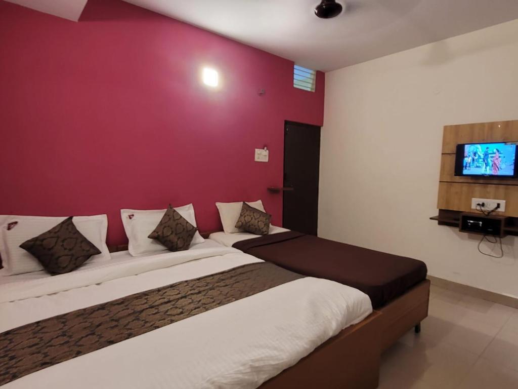 a bedroom with a large bed with a red wall at New Jaganmohana Comforts in Mysore