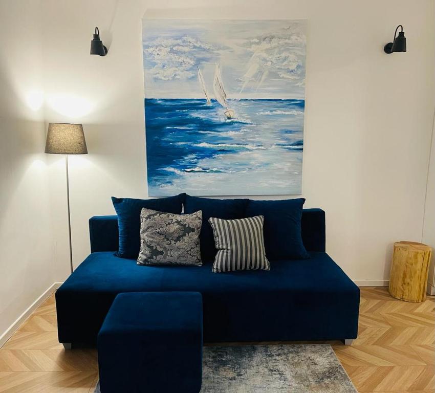 un sofá azul en una sala de estar con una pintura en Łuczański Apartament w sercu Giżycka, en Giżycko
