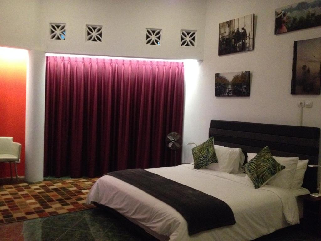 a bedroom with a large bed with a red curtain at Valhalla Bed & Breakfast in Salatiga