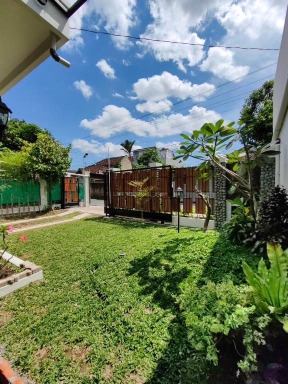 a yard with green grass and a fence at Sekar Tanjung in Yogyakarta