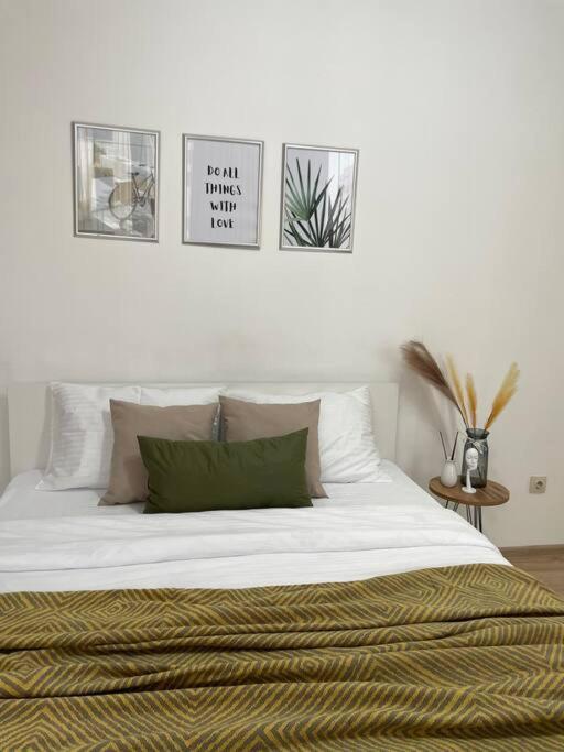 a bedroom with a large white bed with four pictures on the wall at Жк Expo residents in Taldykolʼ