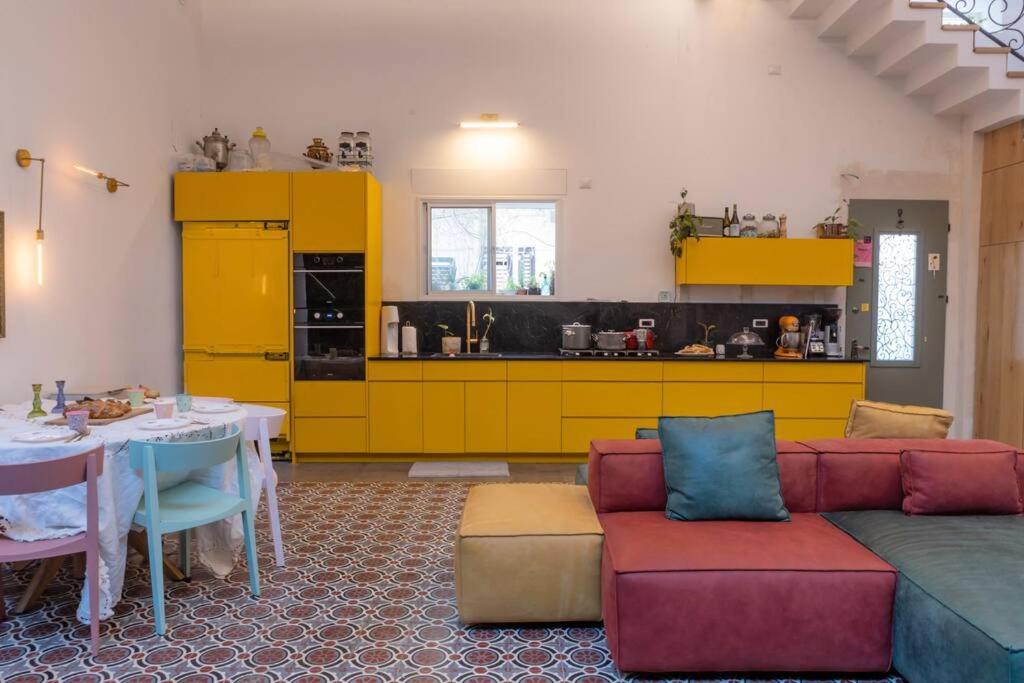 a living room with a couch and a kitchen with yellow cabinets at Tel Aviv Center Seaside Villa with a Pool & Rooftop in Tel Aviv