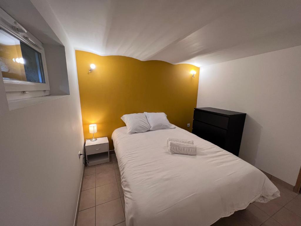 a small bedroom with a white bed and a yellow wall at Maison Climatisée 04 chambres Paris Disney CDG in Gagny