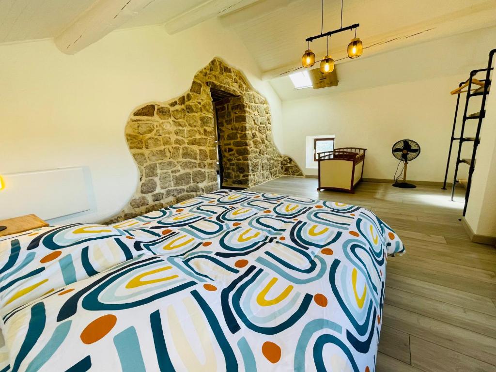 a bedroom with a large bed with a stone wall at Le Planzollais in Planzolles