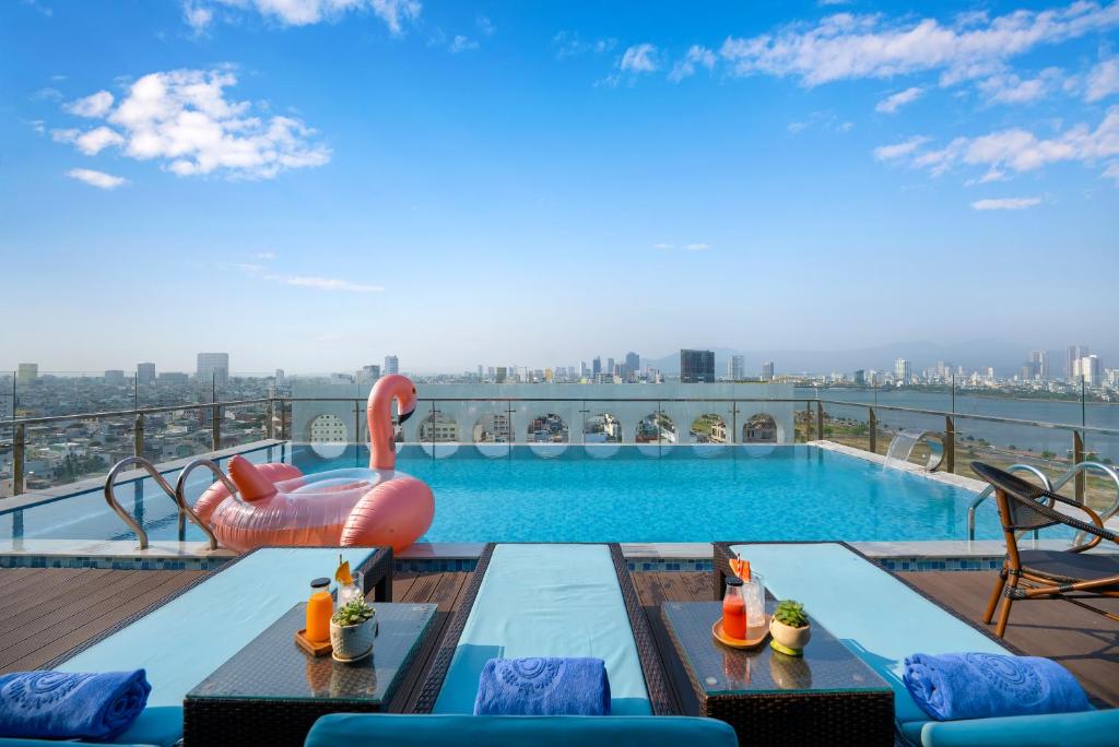 A wide rooftop pool deck with loungers, drinks, and a waterfront city view.