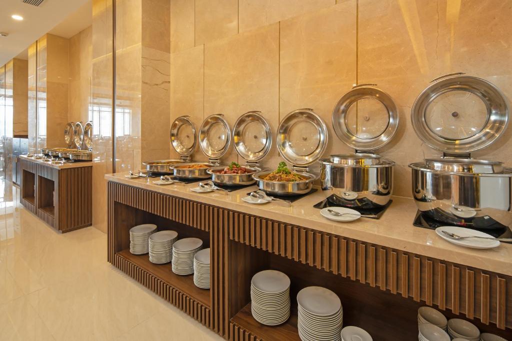 A wall-side hot-food buffet offers covered dishes beside stacks of plates and bowls.