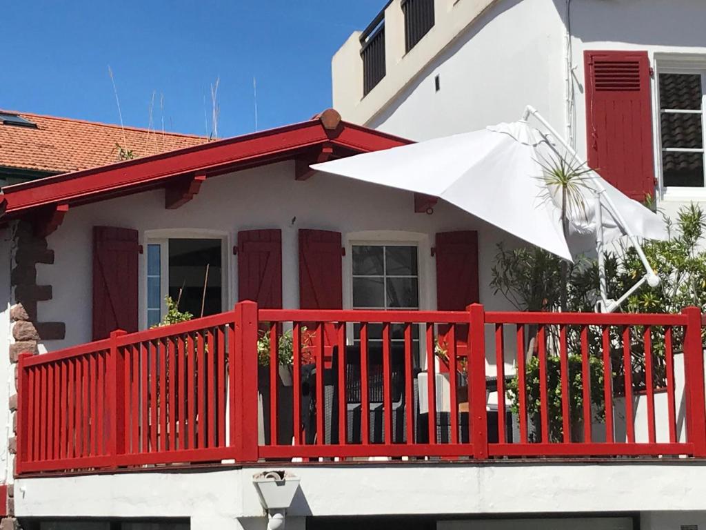 ビダールにあるEn plein coeur du village de Bidart et de ses commerces et à 200 mètres de la mer, un appartement T2 sympaの家の傘付き赤いデッキ