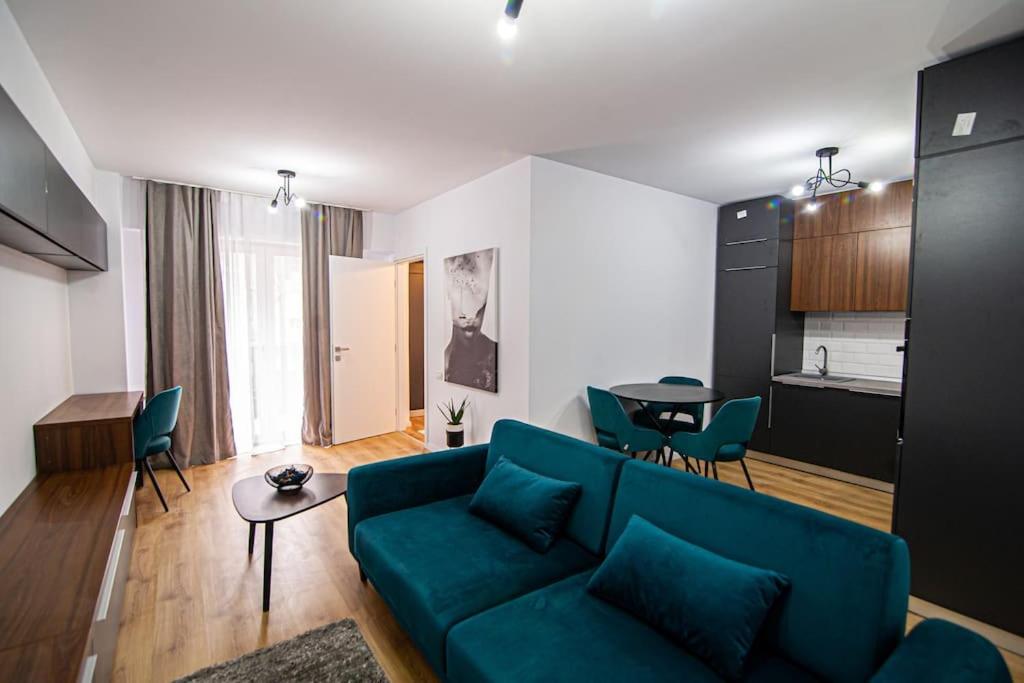 uma sala de estar com um sofá azul e uma cozinha em City Center Accommodation - 410 em Reşiţa