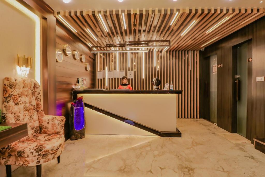 a lobby with a bar and a woman in a mirror at Capital O Western Galaxy in Amritsar