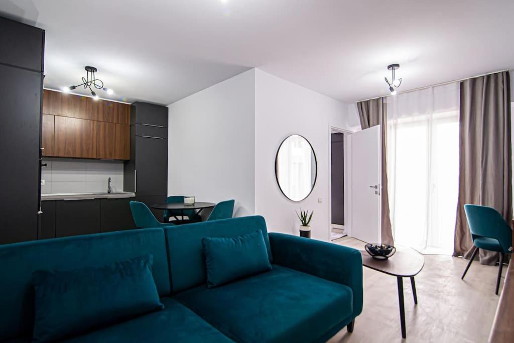 Il comprend un salon avec un canapé bleu et une cuisine. dans l'établissement City Center Accomodation- 401, à Reşiţa