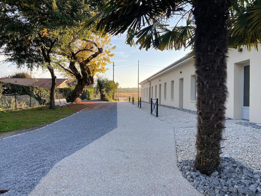 uma passarela com uma palmeira ao lado de um edifício em Appartement 4 au calme dans le Sauternais em Budos