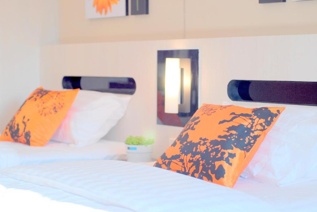 a bedroom with two beds with orange and white pillows at The Inn Saladaeng in Bangkok