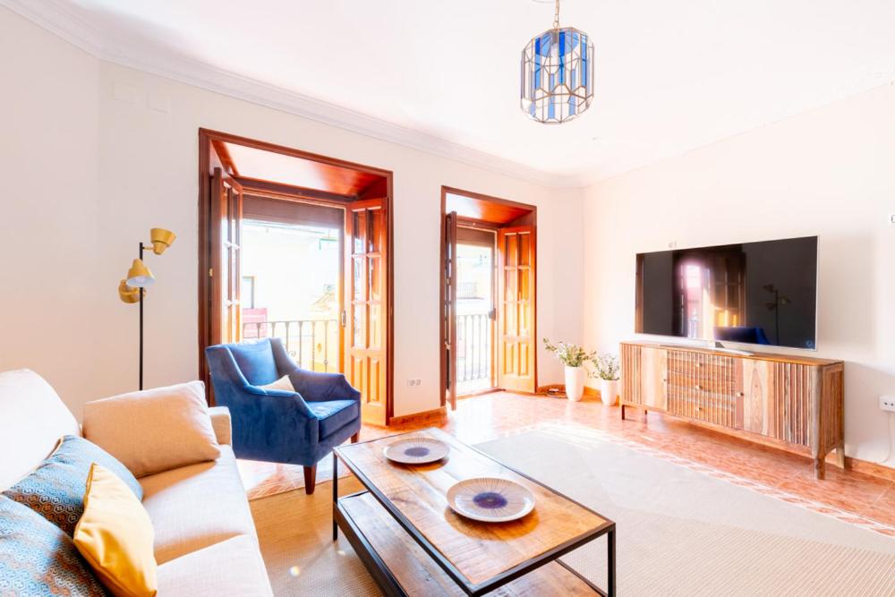 a living room with a couch and a table and a tv at AoA Green Gardens Family House in Seville