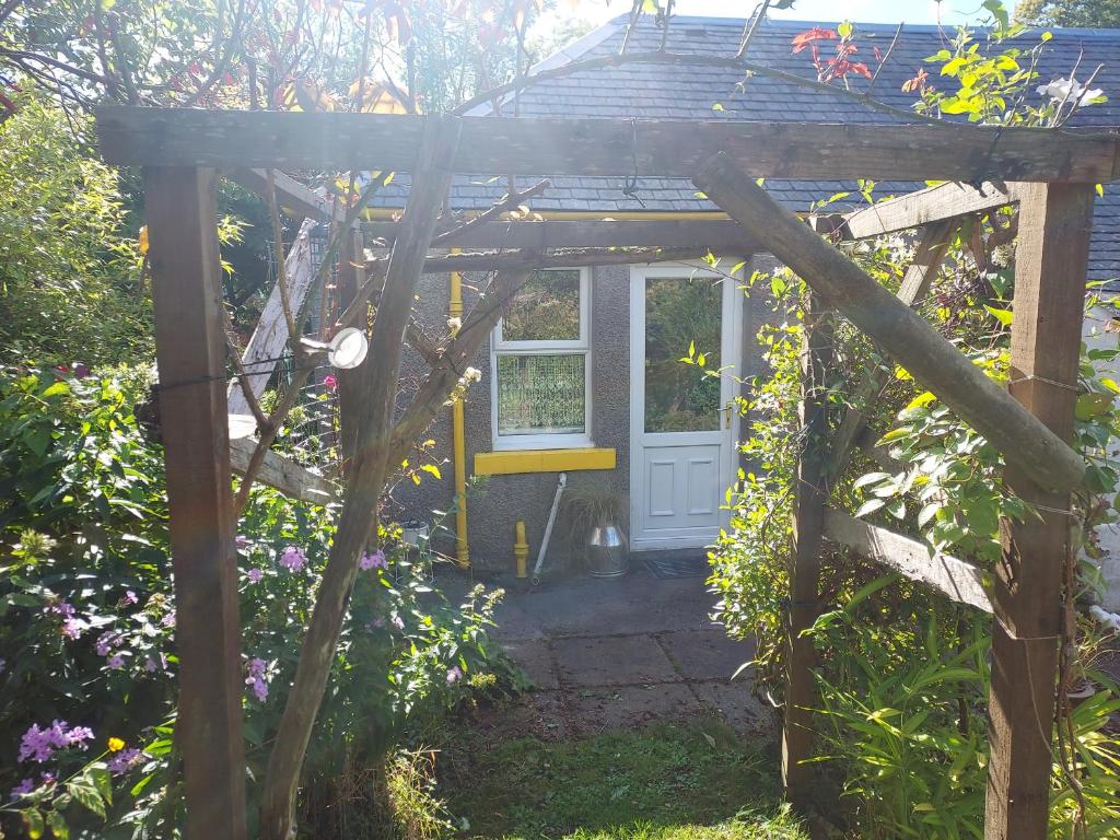 a wooden pergola with a door in a garden at BARHOLM CROFT Holiday Cottage in Creetown