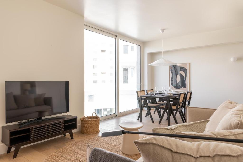a living room with a couch and a tv and a table at Villa Sofia Cascais in Cascais