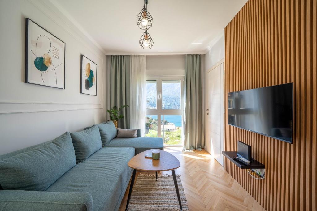 ein Wohnzimmer mit einem blauen Sofa und einem TV in der Unterkunft Luxury D&D Apartment in Kotor
