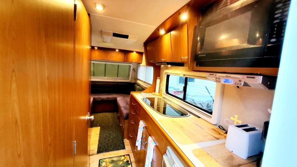 an interior view of an rv with a kitchen and a television at Que Camper Ct Full Bath in New Haven