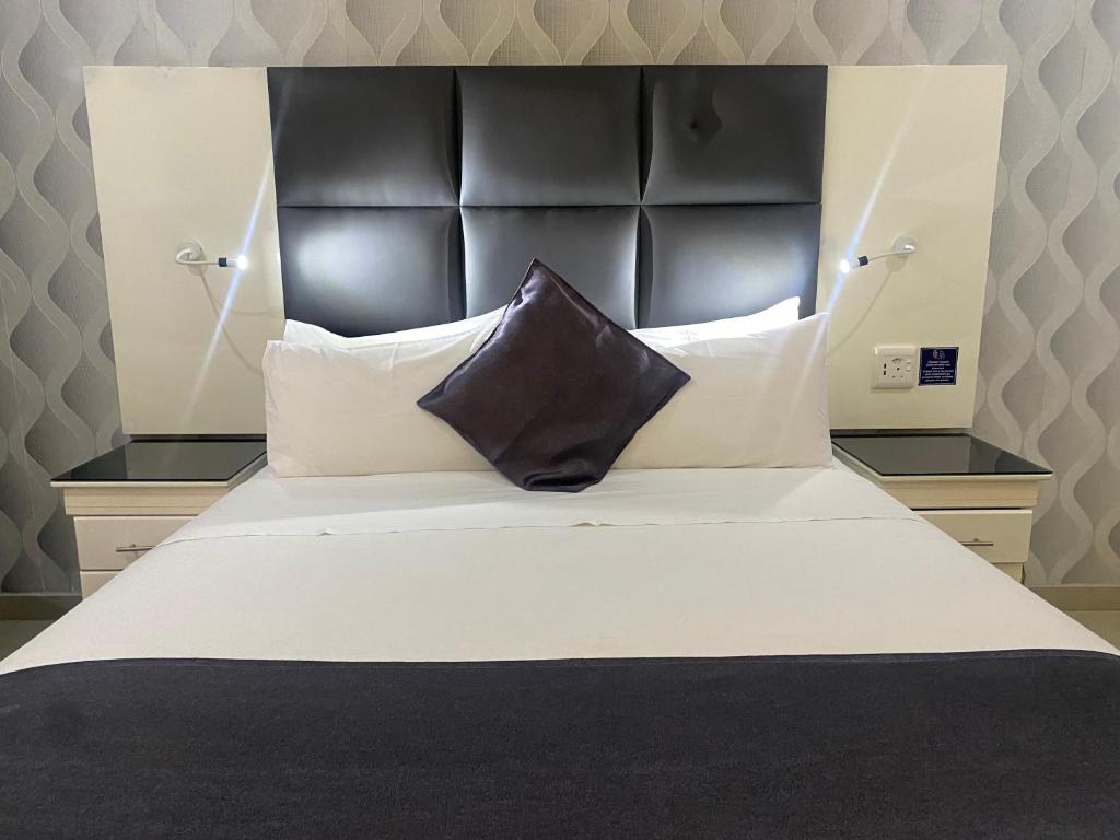 a large bed with a black headboard and white pillows at TETE PALM HOTEL in Tete