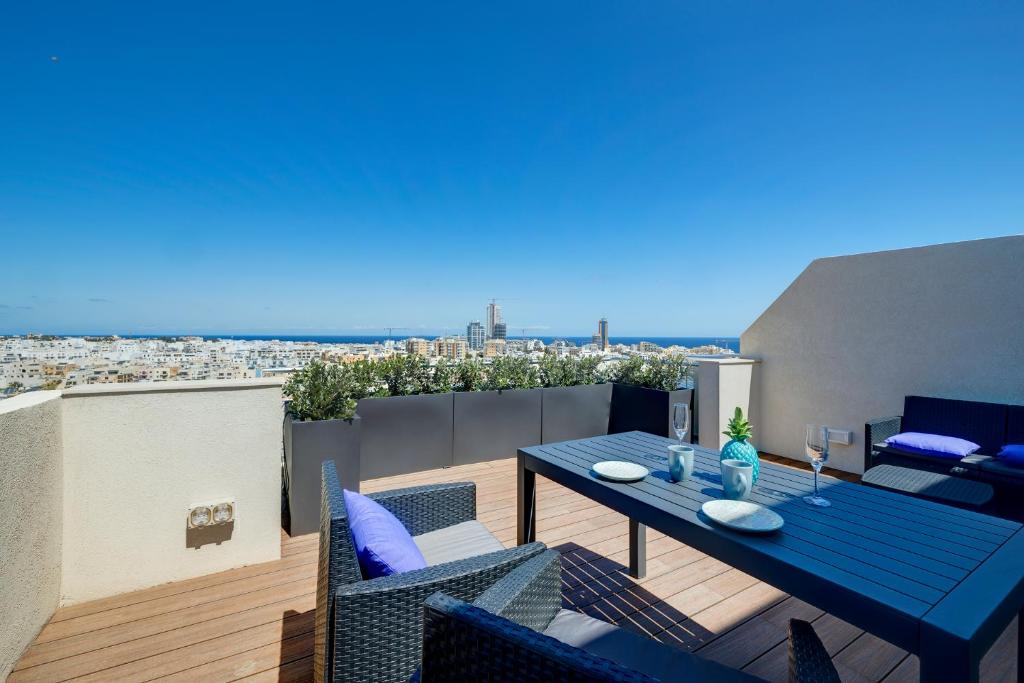 a patio with a blue table and chairs on a balcony at Luxury Penthouse with Terrace and Views in St. Julianʼs