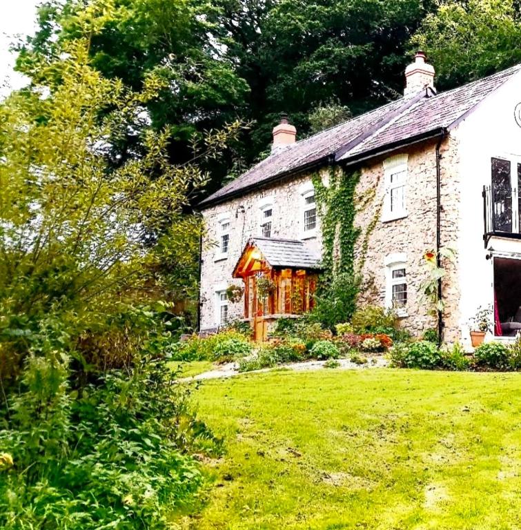 an old stone house with a grass yard at Kingsley Cottage Bed & Breakfast in Beaworthy