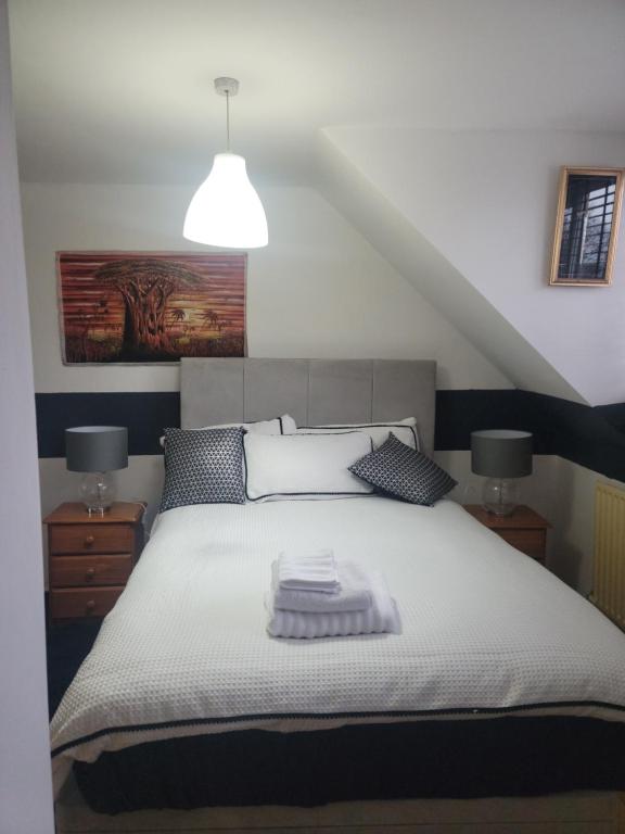 een slaapkamer met een wit bed en 2 lampen bij The Bungalow in Kent