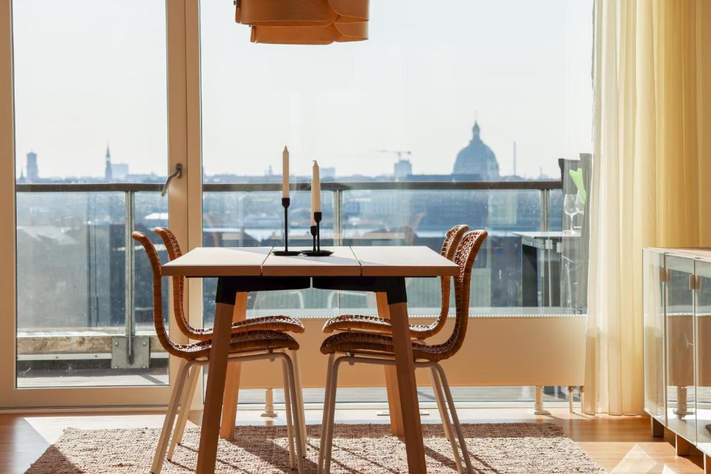 Penthouse - Amazing views & hygge في كوبنهاغن: طاولة طعام مع كراسي ونافذة كبيرة