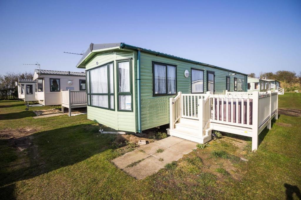 una casa verde y blanca con una valla blanca en 8 Berth Caravan With Wifi At Sunnydale Park In Skegness Ref 35220kc en Louth