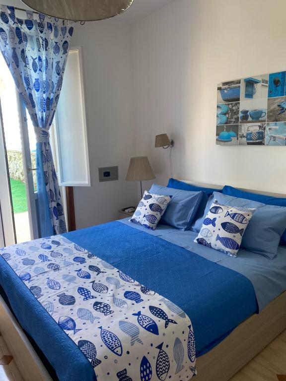 Schlafzimmer mit einem blauen und weißen Bett und einem Fenster in der Unterkunft villa martina apartament in Ischia