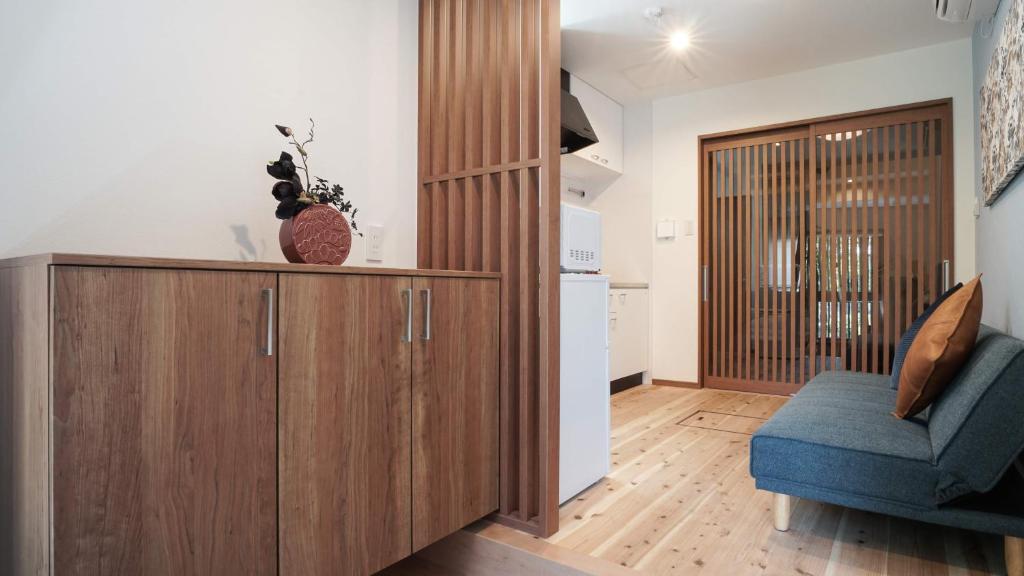 a living room with a wooden cabinet and a blue chair at 伏見稲荷平田町 in Kyoto