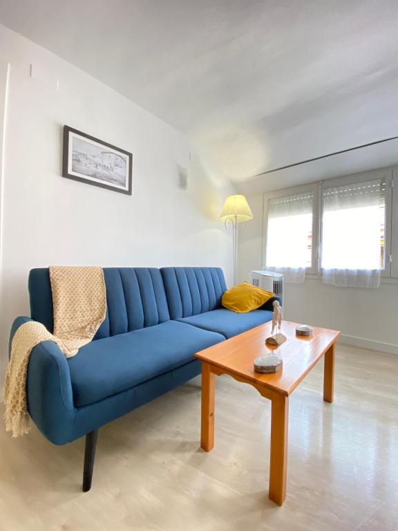 Sofá azul en la sala de estar con mesa en Apartamento en playa de Altafulla, en Altafulla