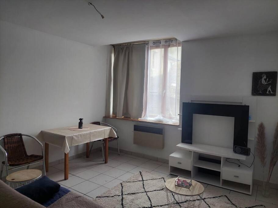 a living room with a tv and a table at Fresnay-sur-Sarthe: joli appartement au calme. in Fresnay-sur-Sarthe