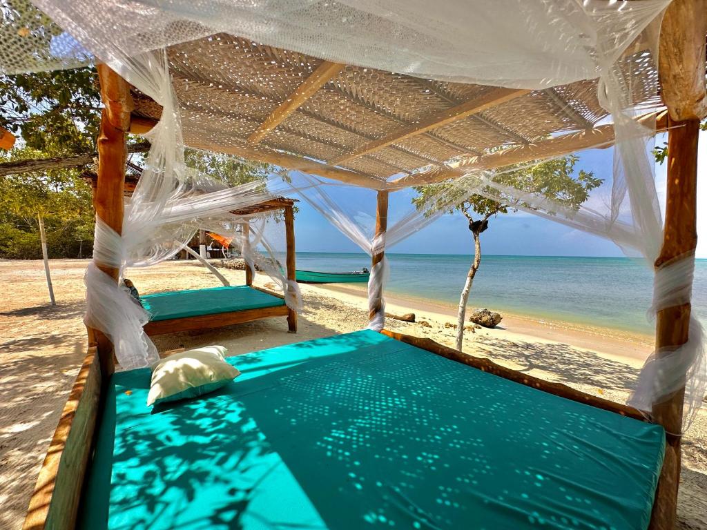 a bed on a beach with the ocean in the background at El Cocotal Tintipán By Ashram in Tintipan Island