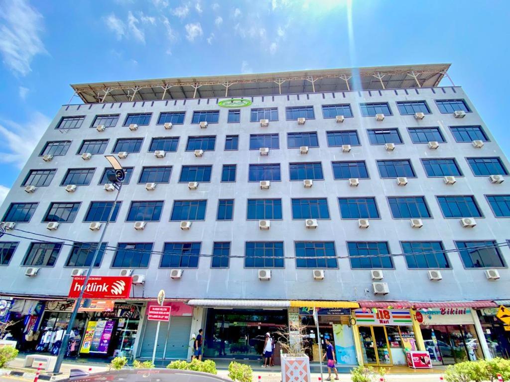 a large white building with blue windows on a street at Langgura Baron Resort in Pantai Cenang