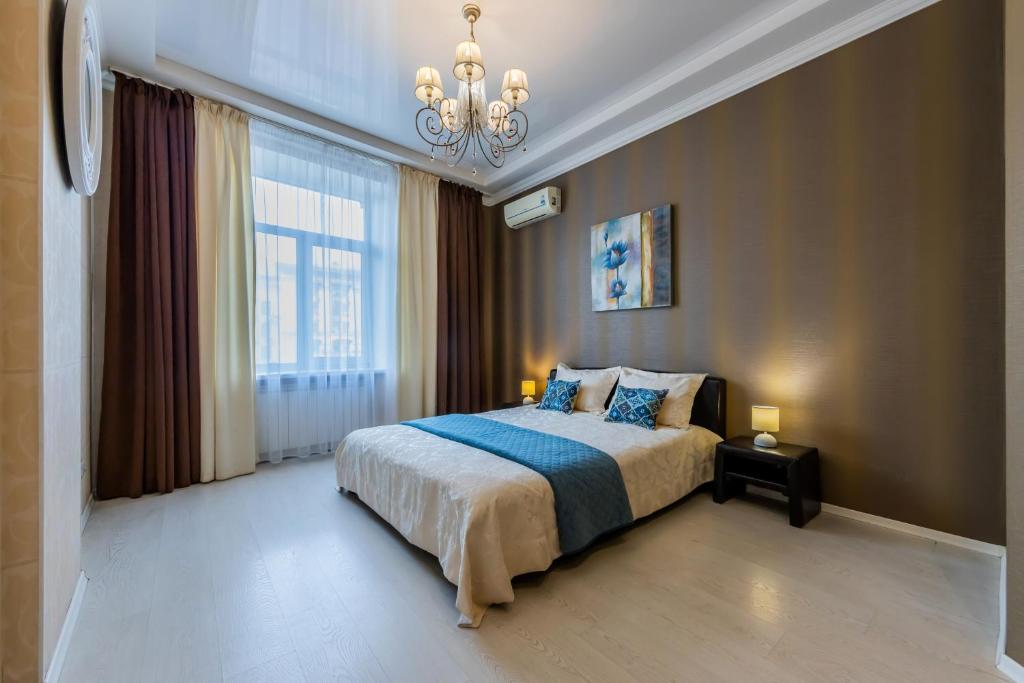 a bedroom with a large bed and a chandelier at 2к квартира із видом на Хрещатик in Kyiv