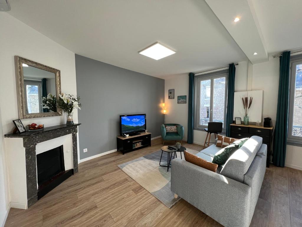 een woonkamer met een bank en een open haard bij Charmant appartement T2 cosy climatisé in Brive-la-Gaillarde