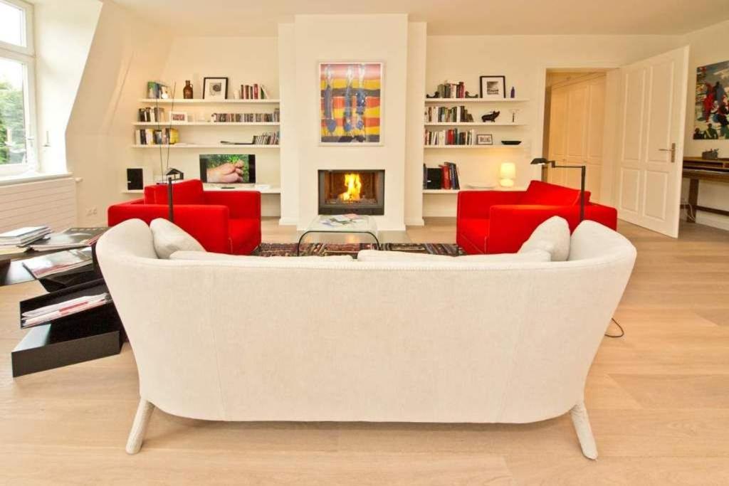 uma sala de estar com um sofá branco e cadeiras vermelhas em Villa Hintze App 13 em Heringsdorf
