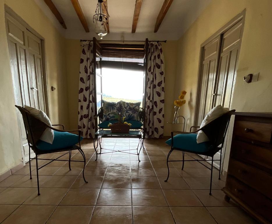 een woonkamer met stoelen, een tafel en een raam bij CORTIJO LOMA DEL BELLOTON in Cazorla