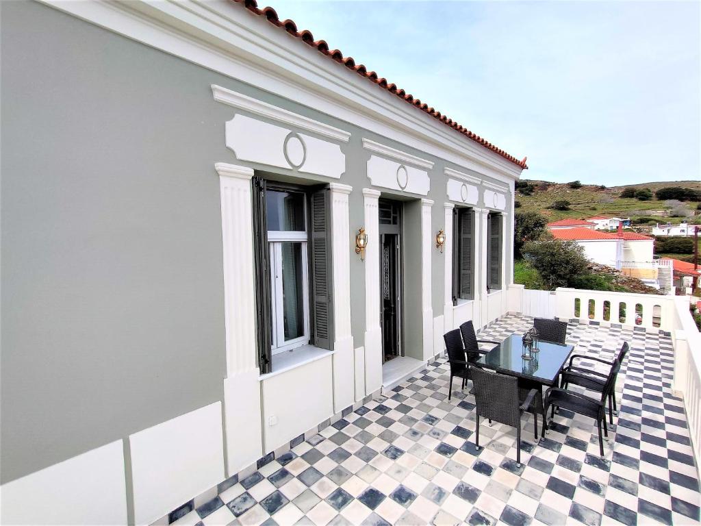 a patio with a table and chairs on a house at Spiti Sea View Neoclassical House in Stenies in Andros